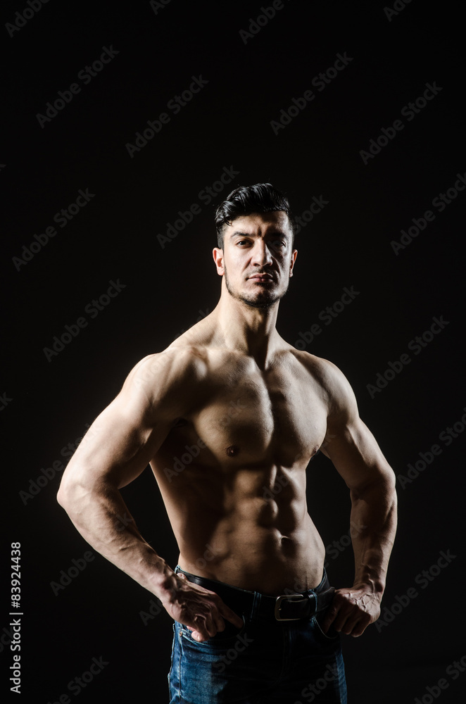Fototapeta premium Muscular man posing in dark studio