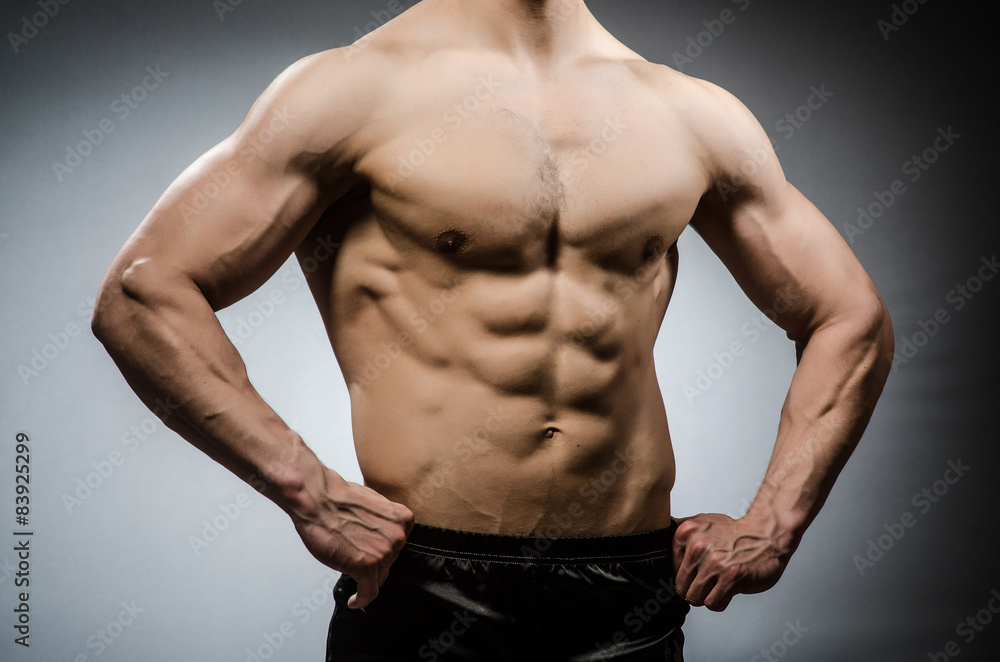 Muscular man posing in dark studio