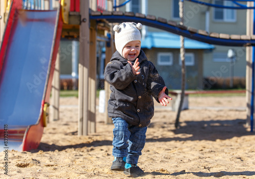 Child shakes off his hands from the sand on playground