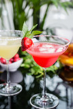 mix of the two bright cocktails: lime daiquiri and strawberry daiquiri on a table with creative decoration of salt on the edge of the glass with fresh mint and lime slices and berries.