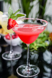 mix of the two bright cocktails: lime daiquiri and strawberry daiquiri on a table with creative decoration of salt on the edge of the glass with fresh mint and lime slices and berries.