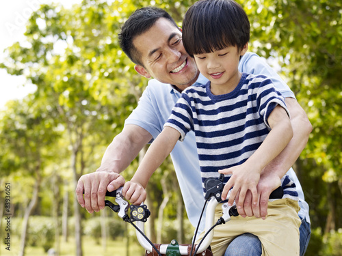 asian father and son enjoying biking outdoors © imtmphoto