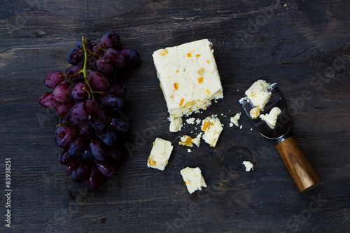 Food background with cheese and grape on dark wooden table.