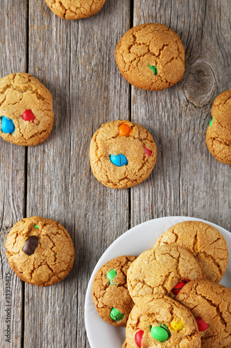 Cookies with colorful candy on plate on grey wooden background