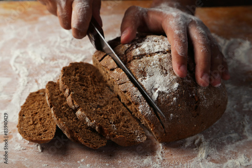 Male hands slicing fresh bread