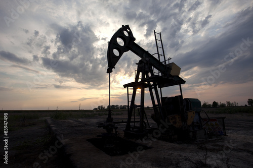 Oil pump in the field at sunset