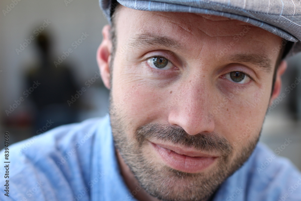 Close up of a smiling man in newsboy hat looking to camera Close up of a smiling man in newsboy hat looking to camera