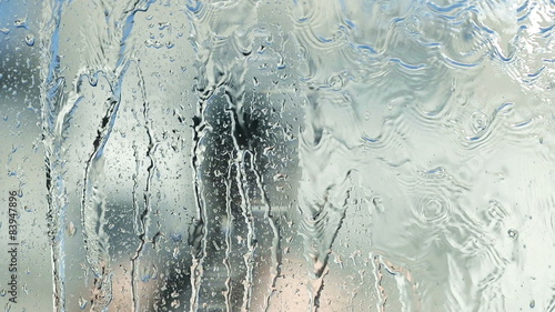 Man cleaning a window with a hose in the summer