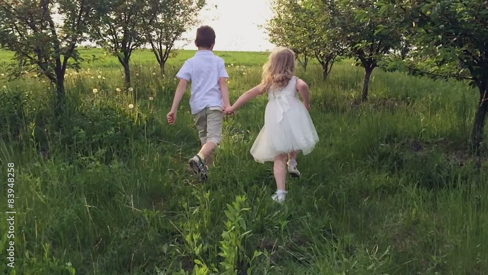 Two children hands running in a spring garden into the sunset Two children hands running in a spring garden into the sunset