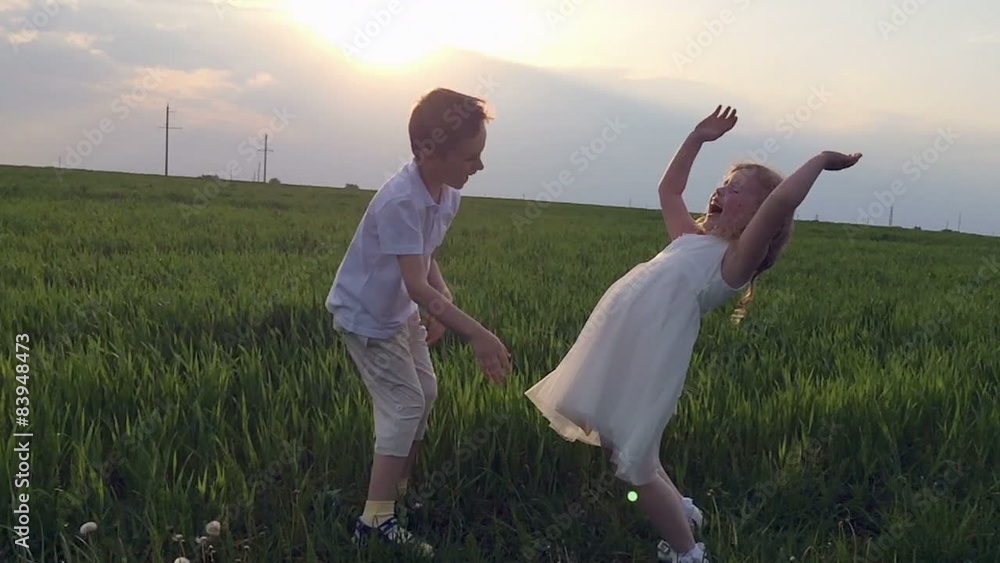 Two happy children playing on meadow, sunset, summertime. Slow Two happy children playing on meadow, sunset, summertime. Slow