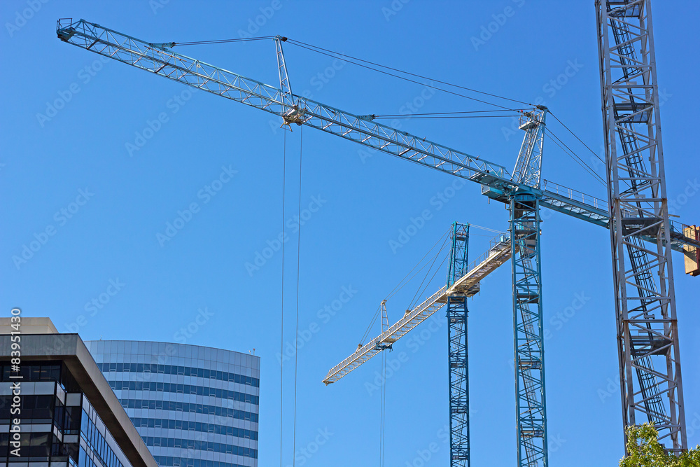 Multiple construction cranes work side by side. Multiple construction cranes work side by side.