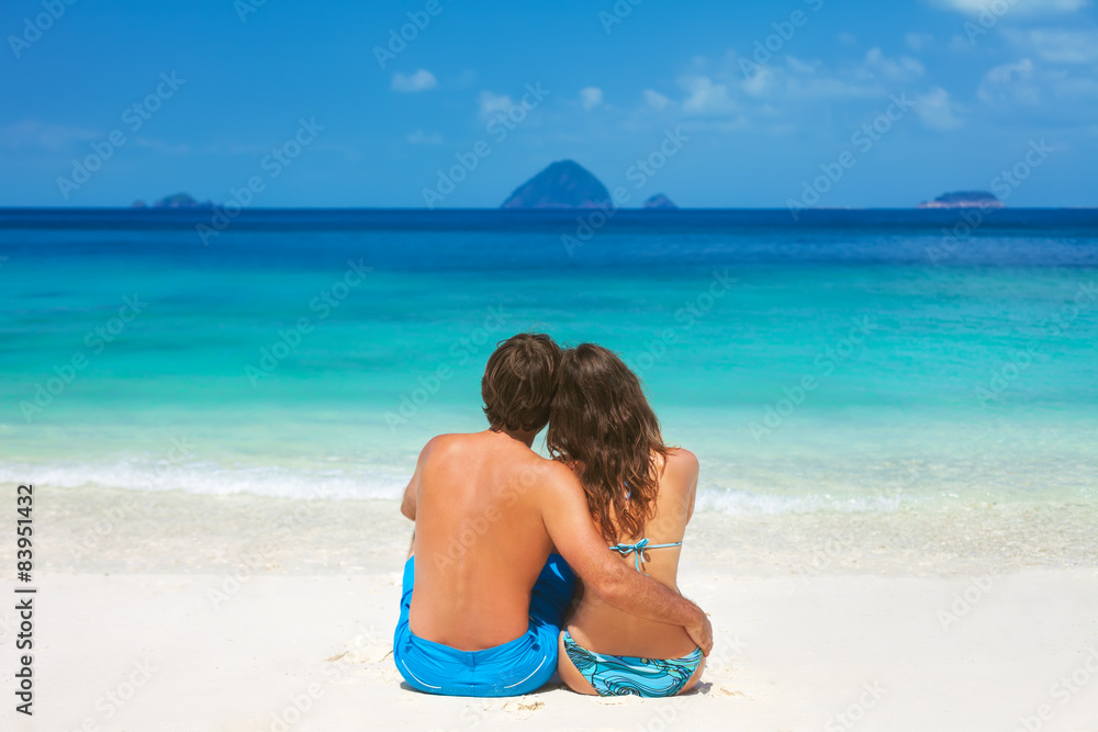 Young couple sitting together on a sandy tropical beach Young couple sitting together on a sandy tropical beach