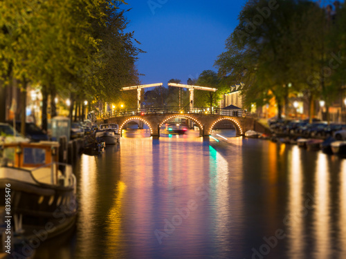 Tilt shift image of skinny bridge on canal in Amsterdam