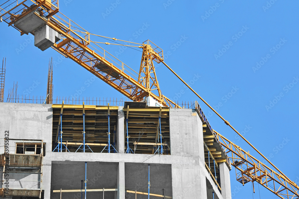 Crane and building construction site against blue sky Crane and building construction site against blue sky
