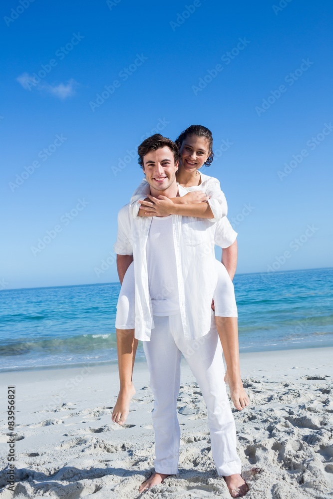 Handsome man giving piggy back to his girlfriend Handsome man giving piggy back to his girlfriend