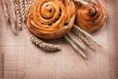 Canvas Print Ripe wheat ears raisin baked rolls on oaken wooden board food an