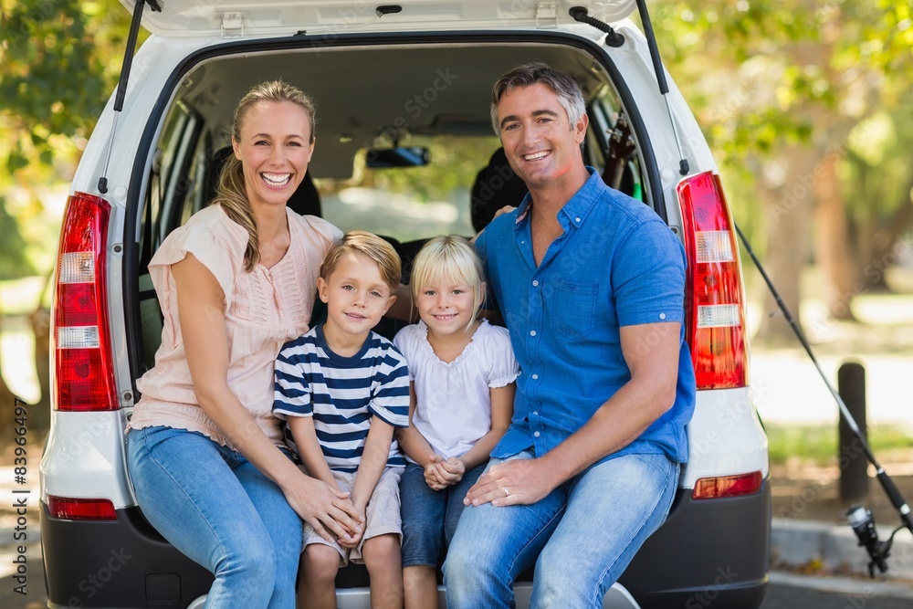 Happy family of four sitting in car trunk Happy family of four sitting in car trunk