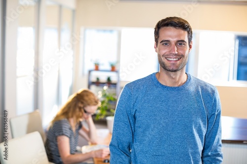 Smiling casual businessman posing with his partner behind 