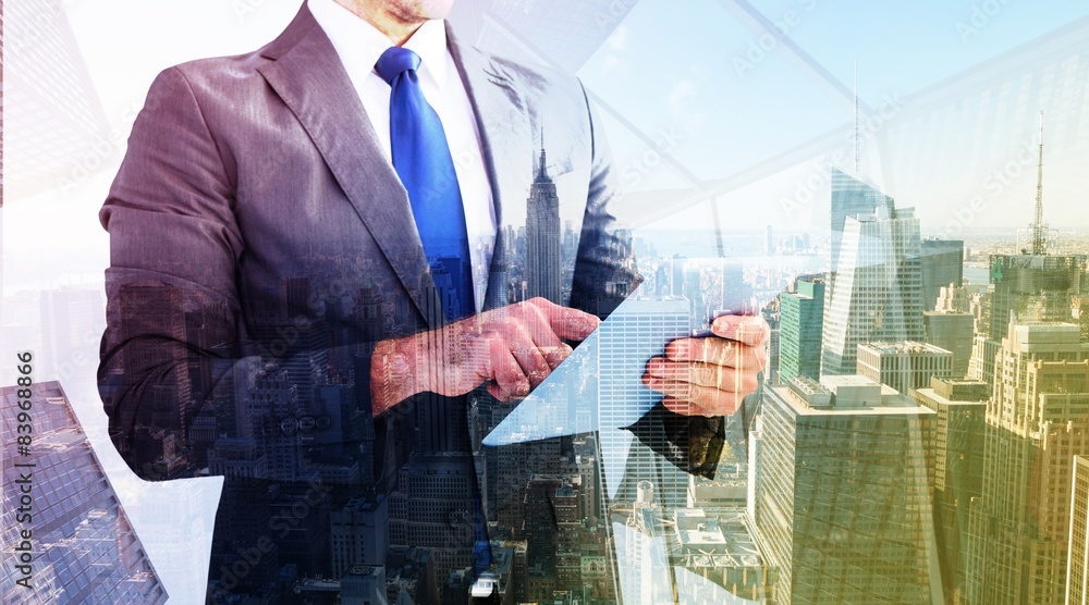 Composite image of businessman using his tablet pc Composite image of businessman using his tablet pc