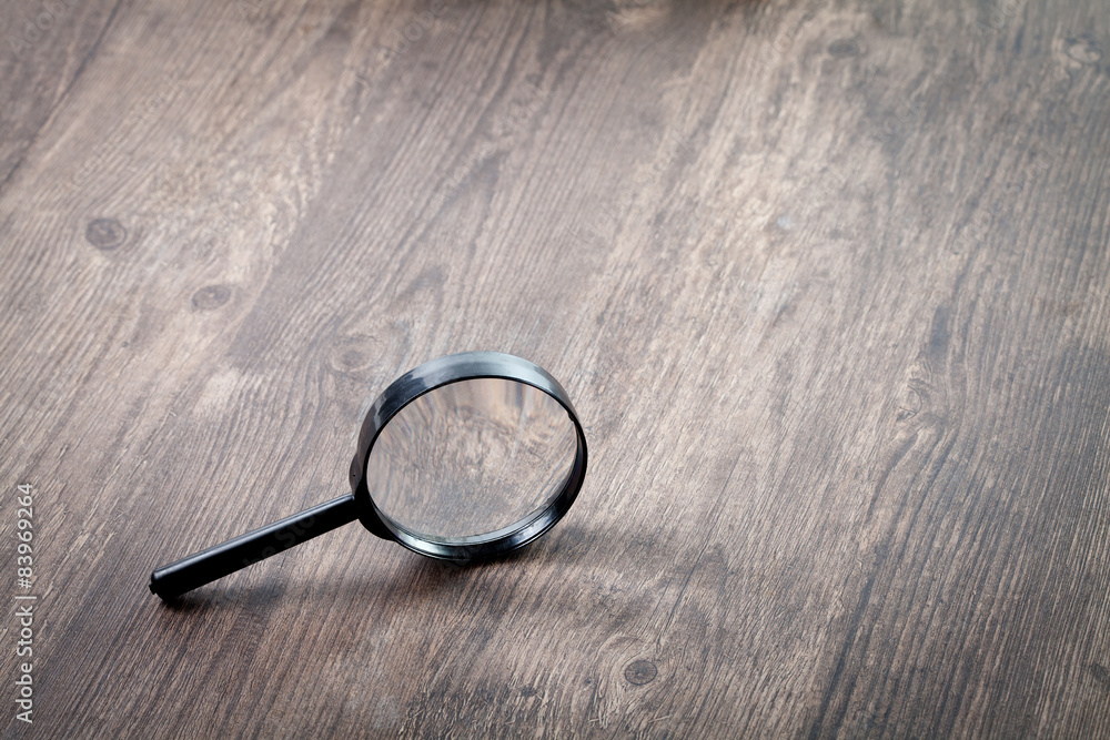 Fototapeta premium Magnifying glass on wooden table, Search and discover symbol