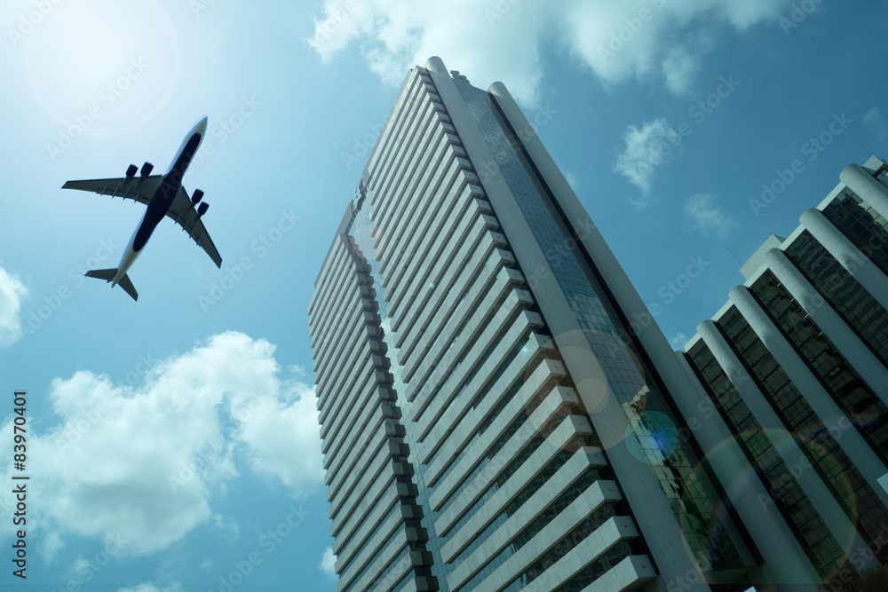 Fototapeta premium Airplane in the sky with modern buildings