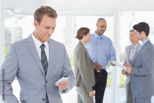 Businessman texting while his colleagues discussing