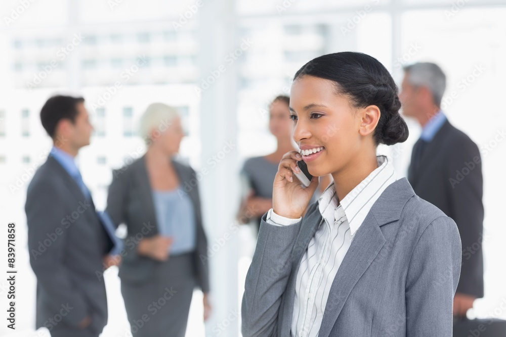 Businesswoman using mobile phone with colleagues behind Businesswoman using mobile phone with colleagues behind