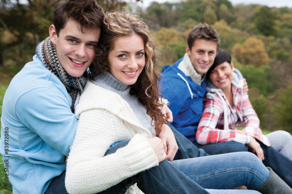 Two couples sit together outside and smile for the camera.