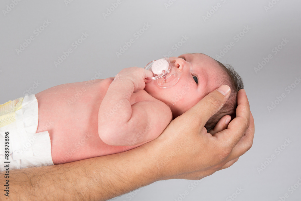 New born baby is held by his father isolated on grey New born baby is held by his father isolated on grey