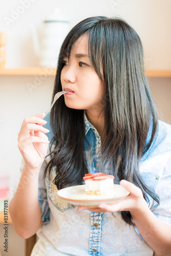 Portrait of young asian pretty smiling woman eating cake at cafe