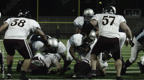 A running back takes a hand off from the QB dives over the line of scrimmage 