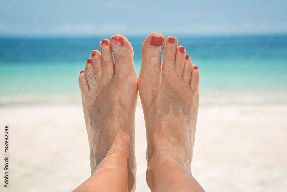 Woman bare sandy feet, beach and sea in the background Woman bare sandy feet, beach and sea in the background