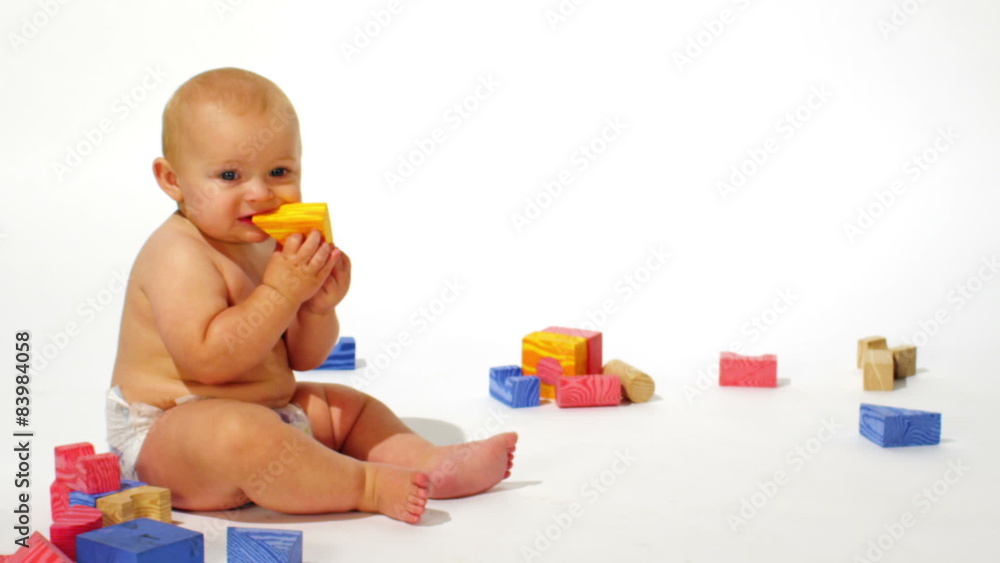A cute baby boy sits and plays with toys on a white background A cute baby boy sits and plays with toys on a white background