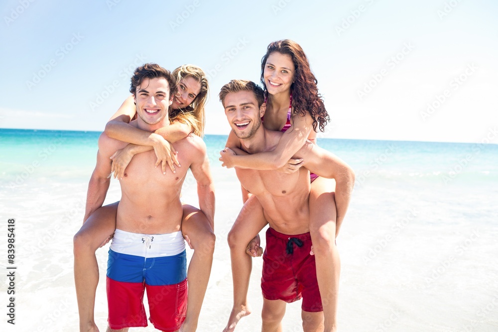 Handsome men giving piggy back to their girlfriends Handsome men giving piggy back to their girlfriends