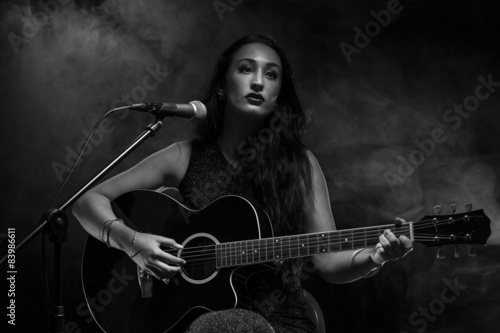 Beautiful young lady playing acoustic guitar