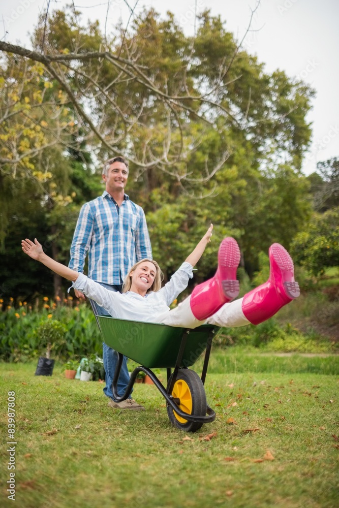 Happy couple playing with a wheelbarrow Happy couple playing with a wheelbarrow