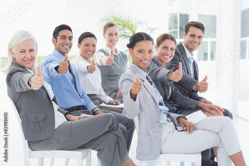 Business people looking at camera with thumbs up 