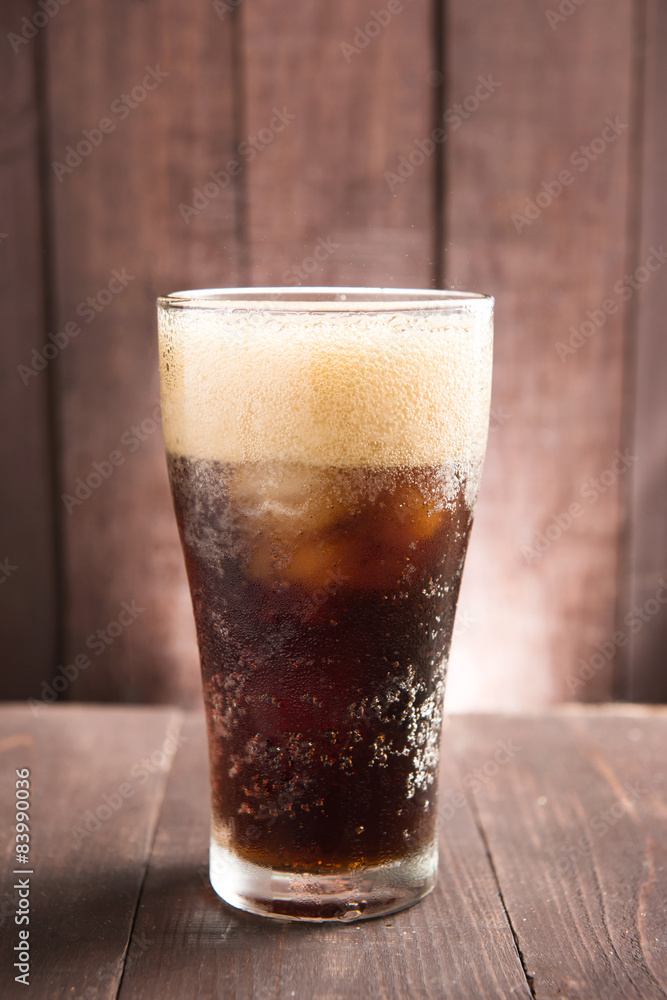 Cola in glass with ice on wooden background Cola in glass with ice on wooden background