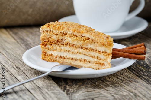 Tasty honey cake with cup of coffee on wooden background.