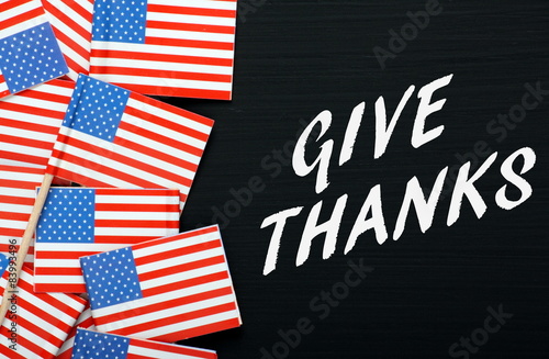 The phrase Give Thanks on a blackboard with USA flags