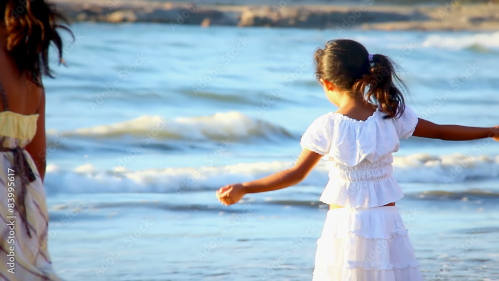 Young girls walk into the surf on a beach in Mexico during sunset