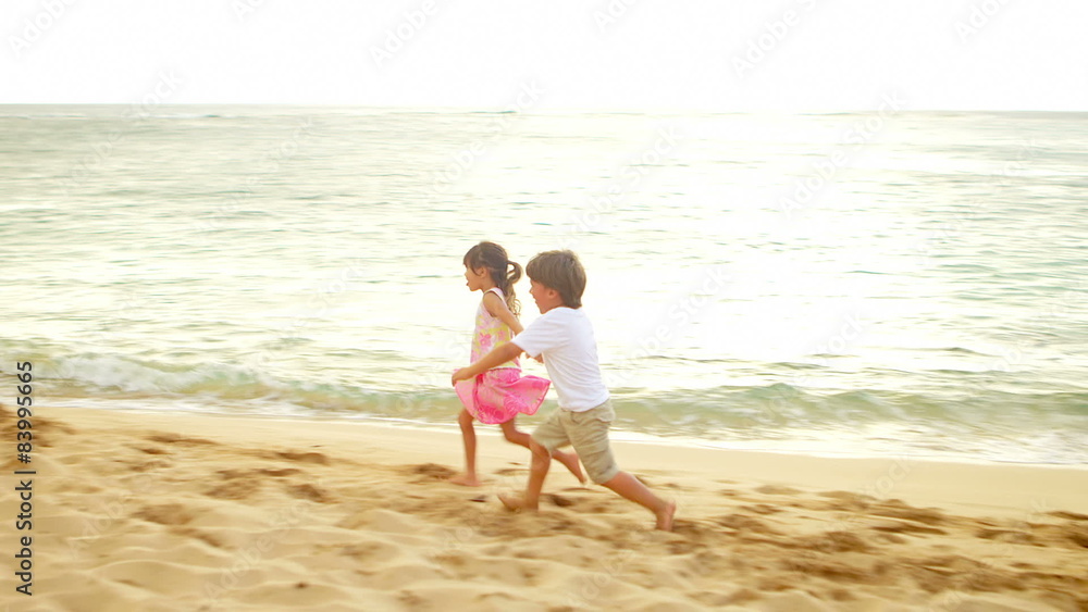 A boy and girl run down the beach and into their parents' arms A boy and girl run down the beach and into their parents' arms