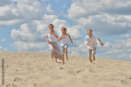 Mother with her sons running on a sand 