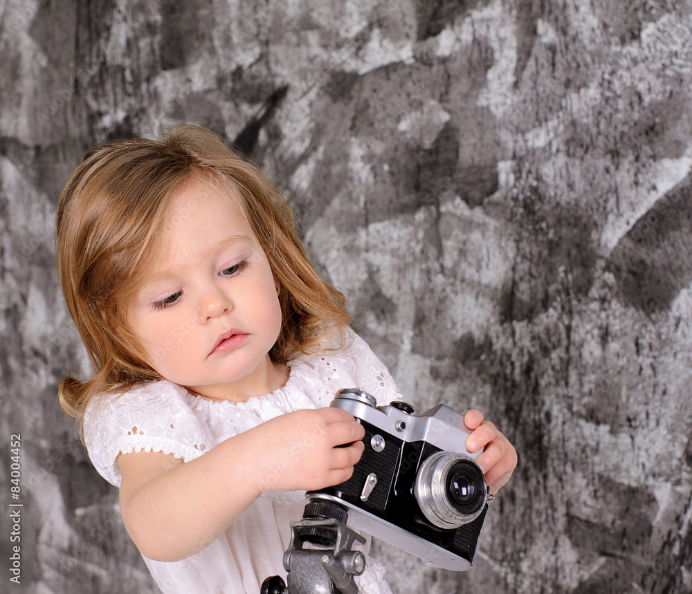 little girl with retro camera on rack indoors