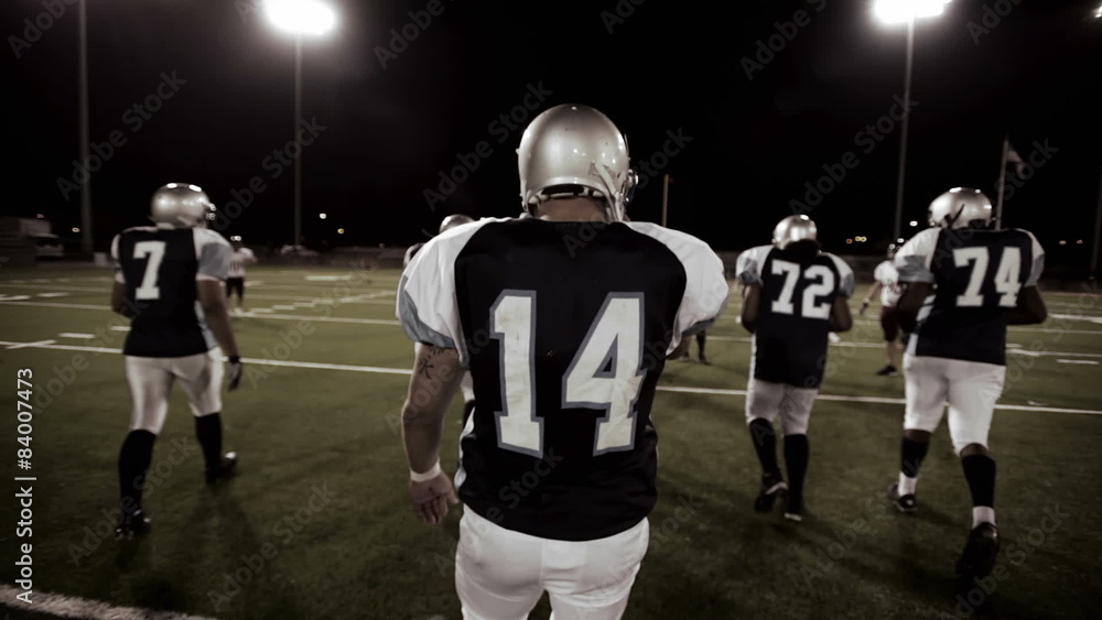 Over the shoulder view of a quarterback in the huddle and walking to the line Over the shoulder view of a quarterback in the huddle and walking to the line