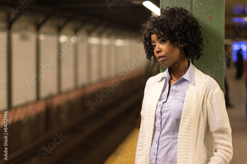 Young African American black woman in city at night waiting for subway train