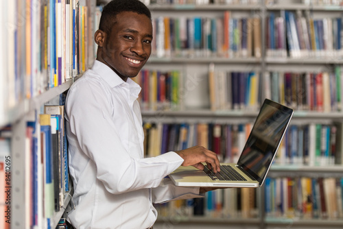 Young Student Using His Laptop In A Library