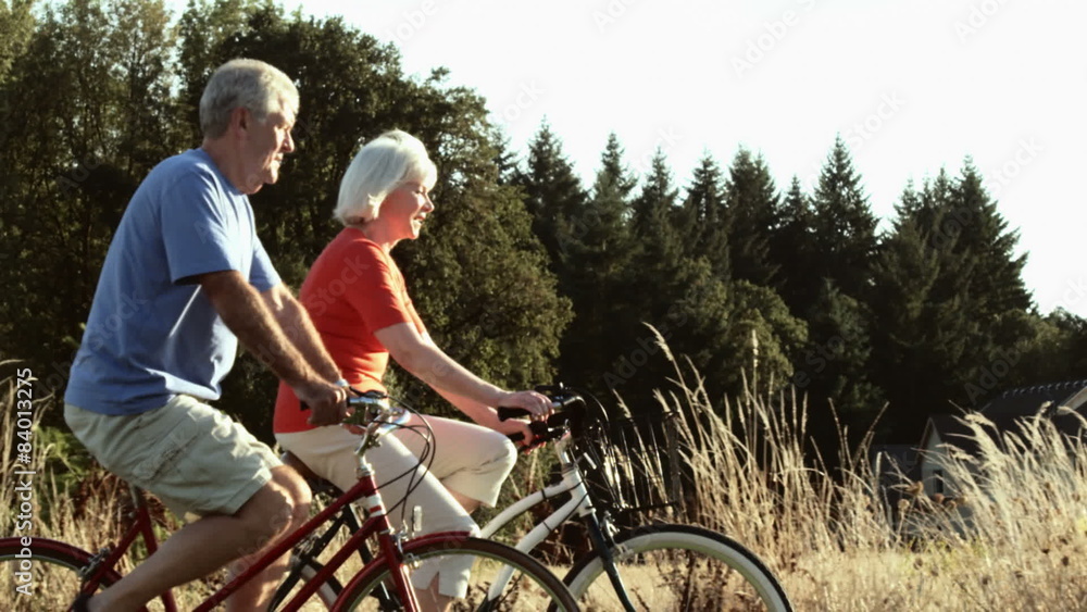 Senior couple enjoy time together bike riding. Wide shot. Senior couple enjoy time together bike riding. Wide shot.