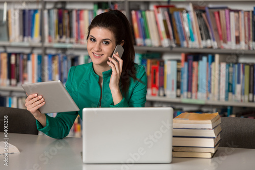 Beautiful College Student Using Mobile Phone In Library