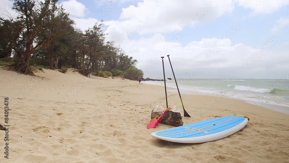 Tranquil scene of a beach with a surf board in center frame. Wide shot. Tranquil scene of a beach with a surf board in center frame. Wide shot.